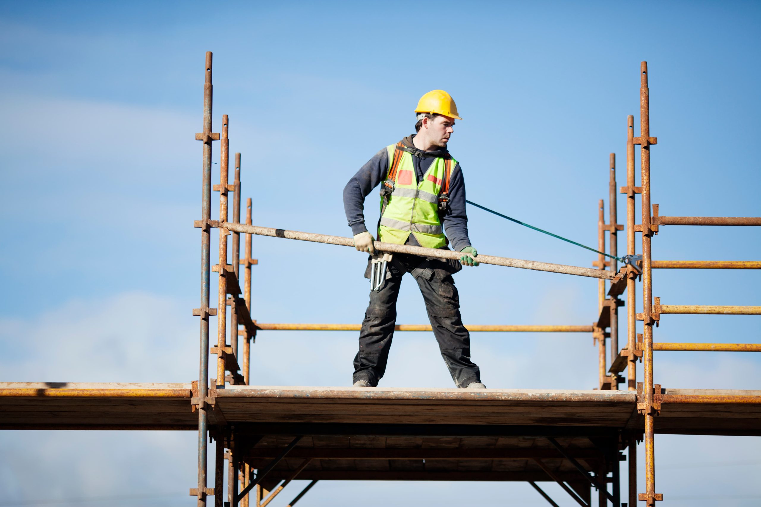 Construction worker setting up scaffolding against the sky